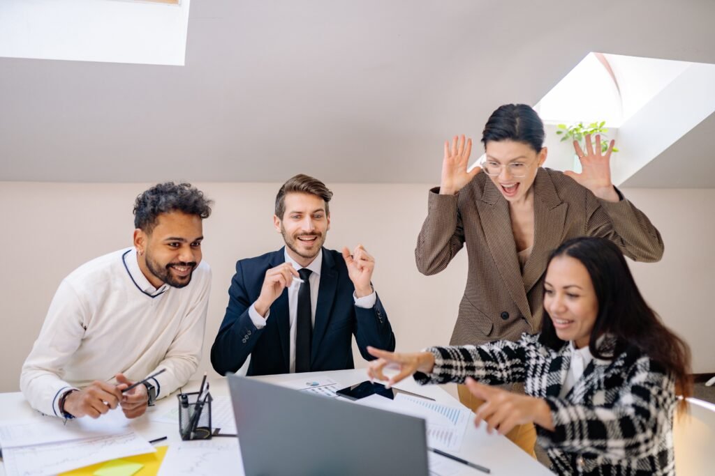 Happy diverse team of colleagues celebrating success in a modern office setting.